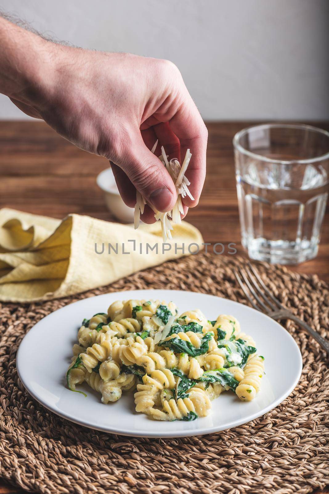 Fusilli Pasta with Spinach and Ricotta Garnished with Grated Parmesan Cheese on White Plate