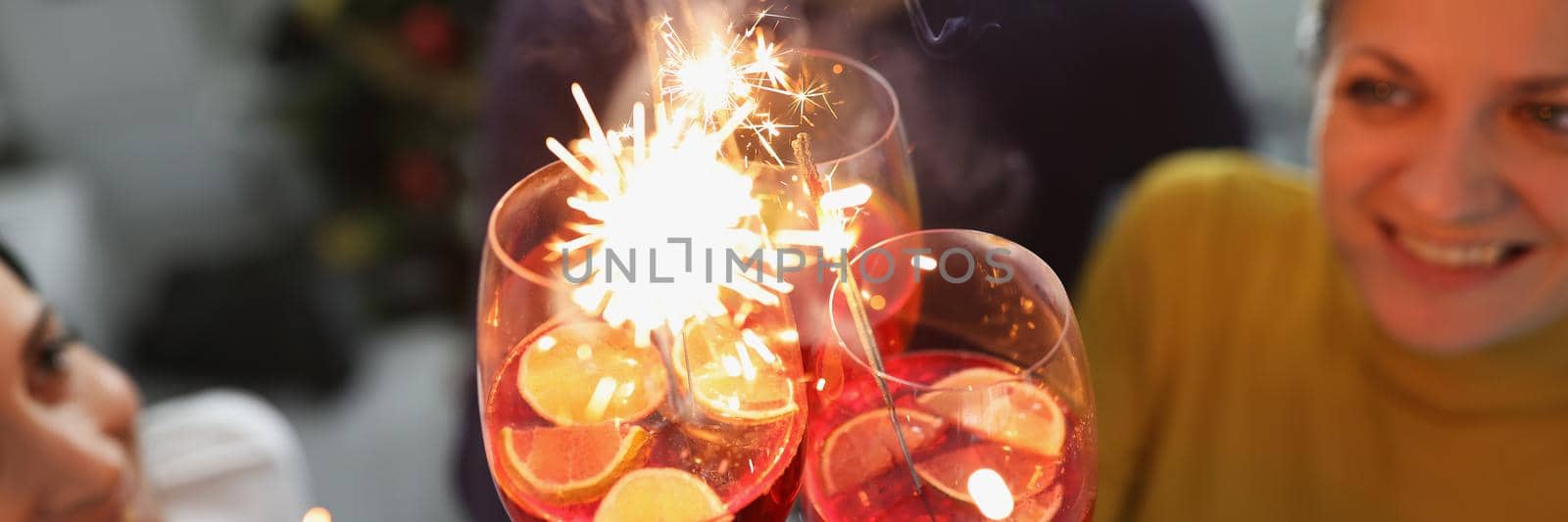 Close-up of friends celebrating new year coming raising glasses and make toast. Happy atmosphere in family circle, home party. Christmas, holiday concept