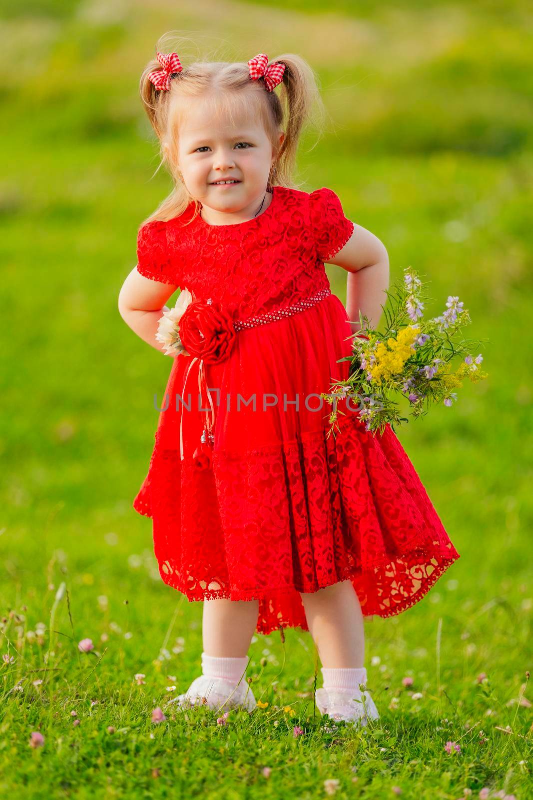 girl in a red dress and with a bouquet of wild flowers on the lawn