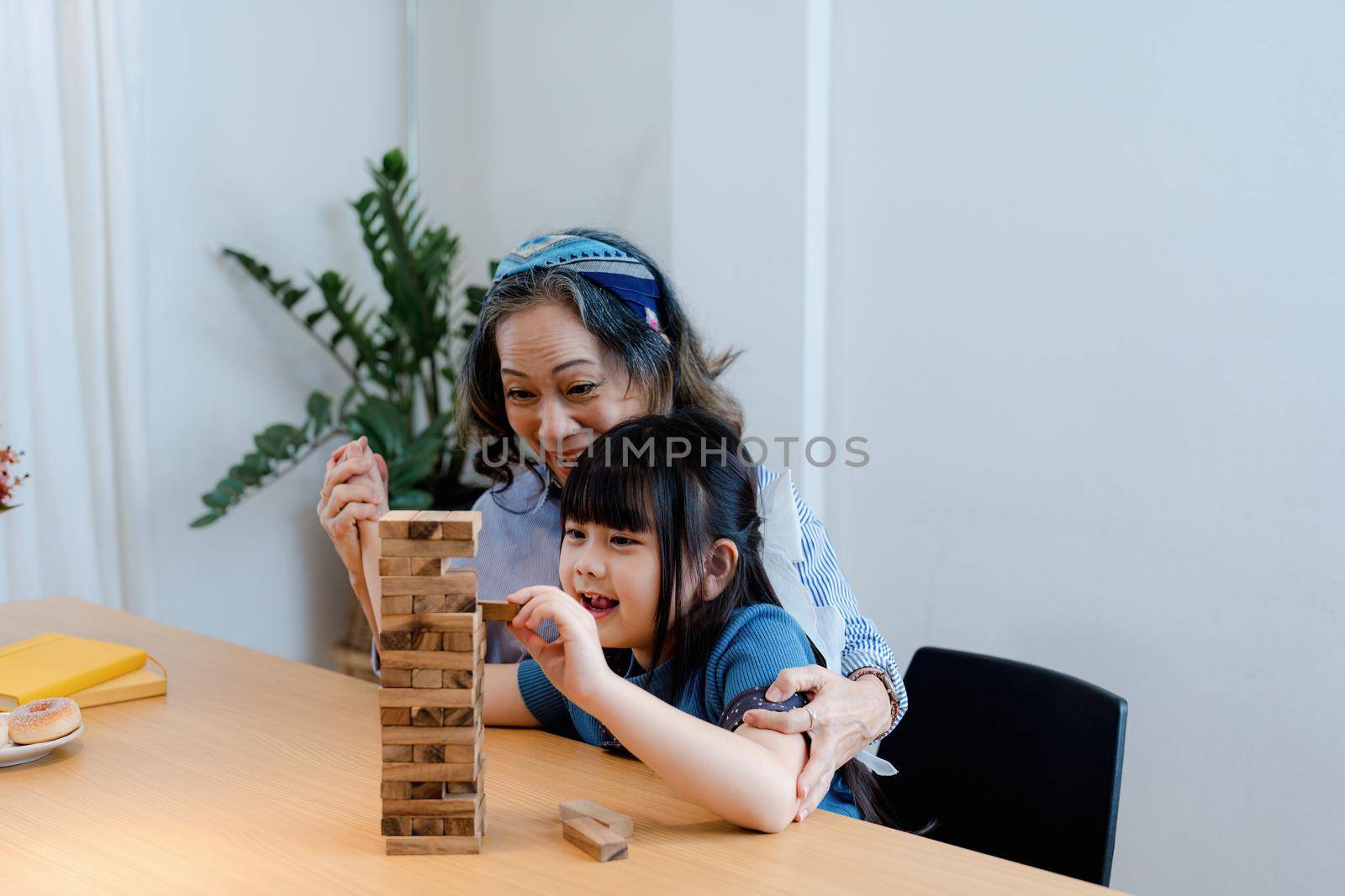 Asian portrait, grandchild granddaughter grandma grandmother and granddaughter happily join in activities to Block wood game Puzzle and enhance skills for grandchildren.