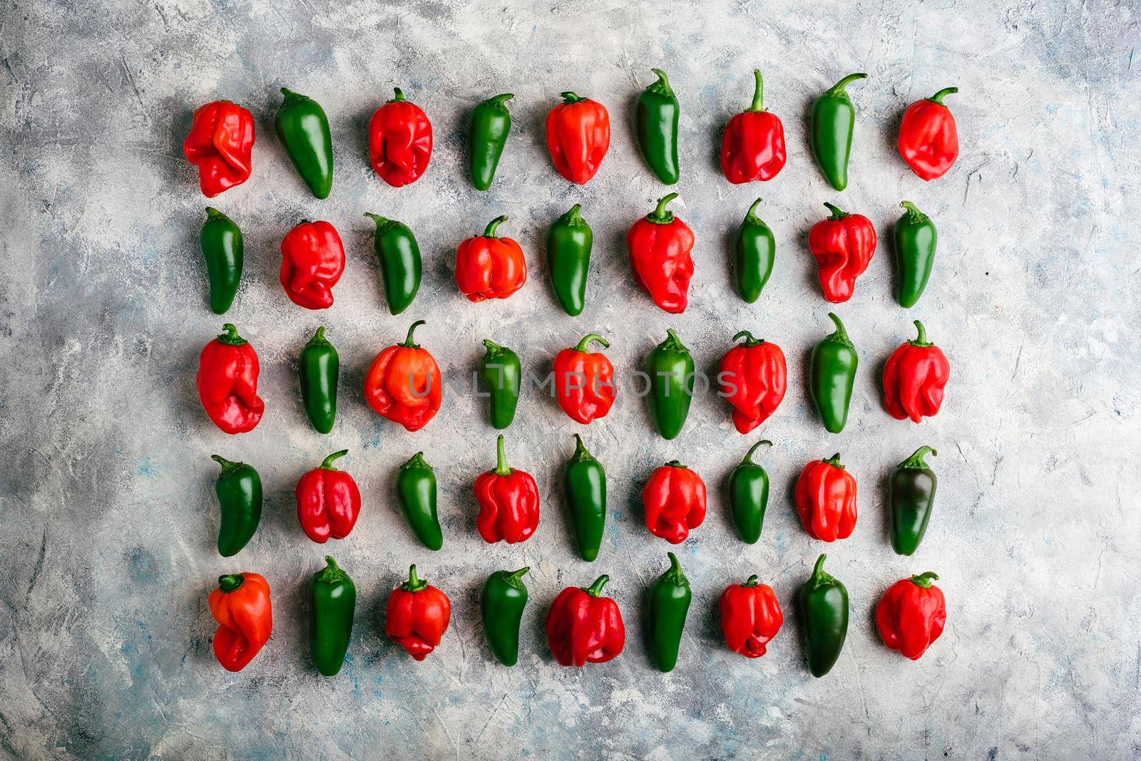Sorted Green Jalapeno and Red Habanero Peppers on Light Concrete Surface. View from Above