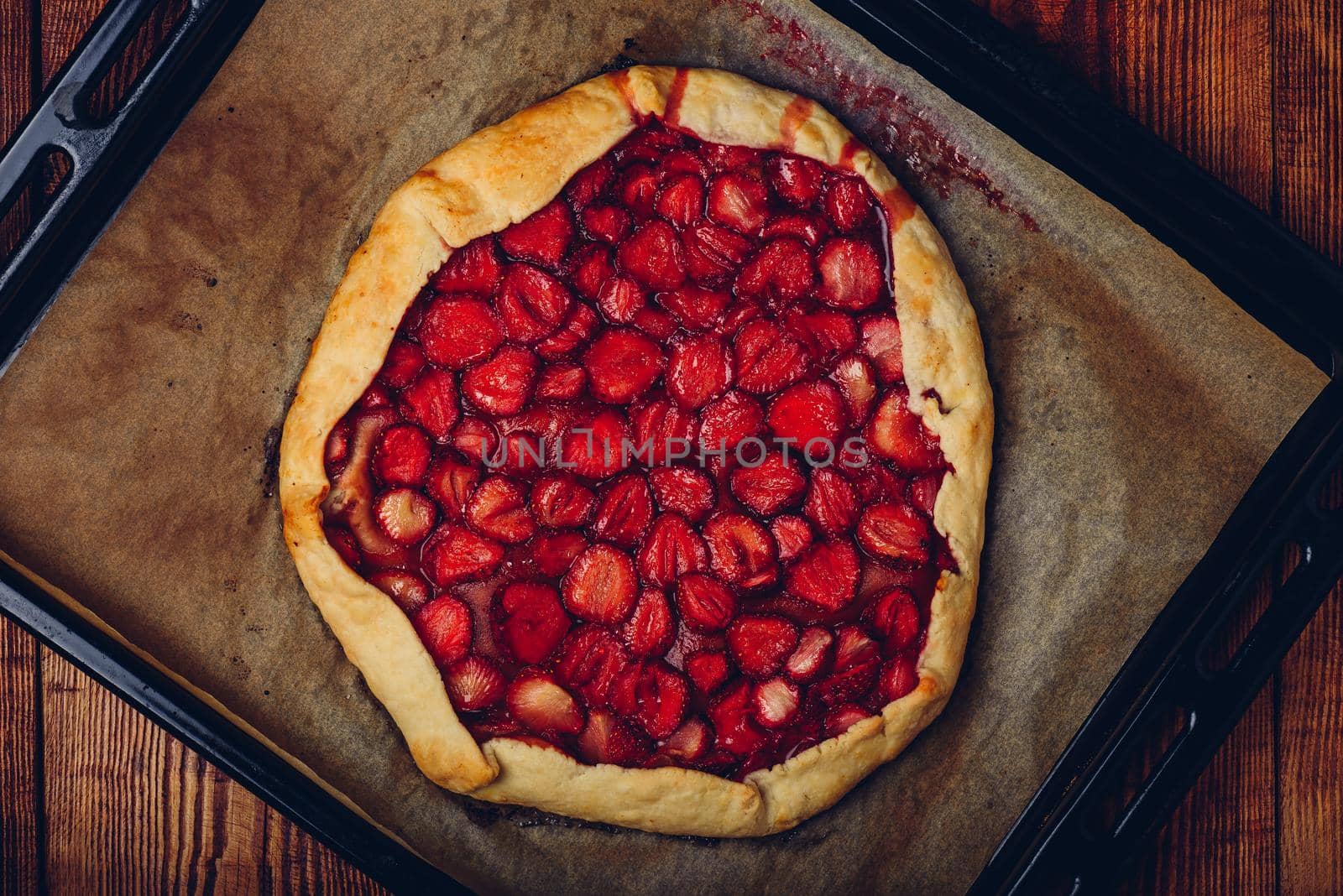 Close Up Of Fresh Baked Strawberry Galette On Baking Sheet Over Wooden Table. View from Above