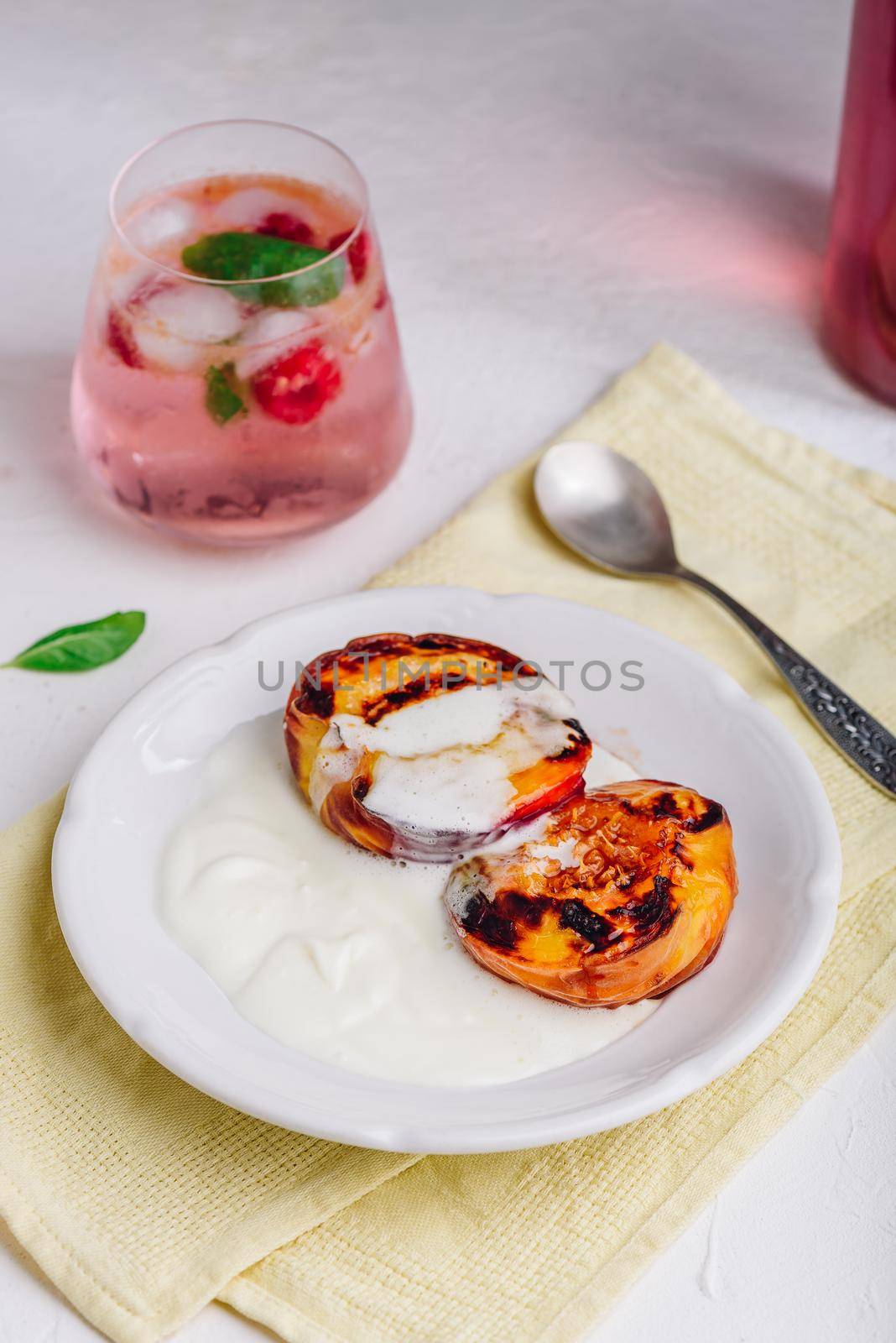 Served Oven Roasted Peaches with Honey and Whipped Heavy Cream on White Plate and Glass of Raspberry, Mint Mocktail