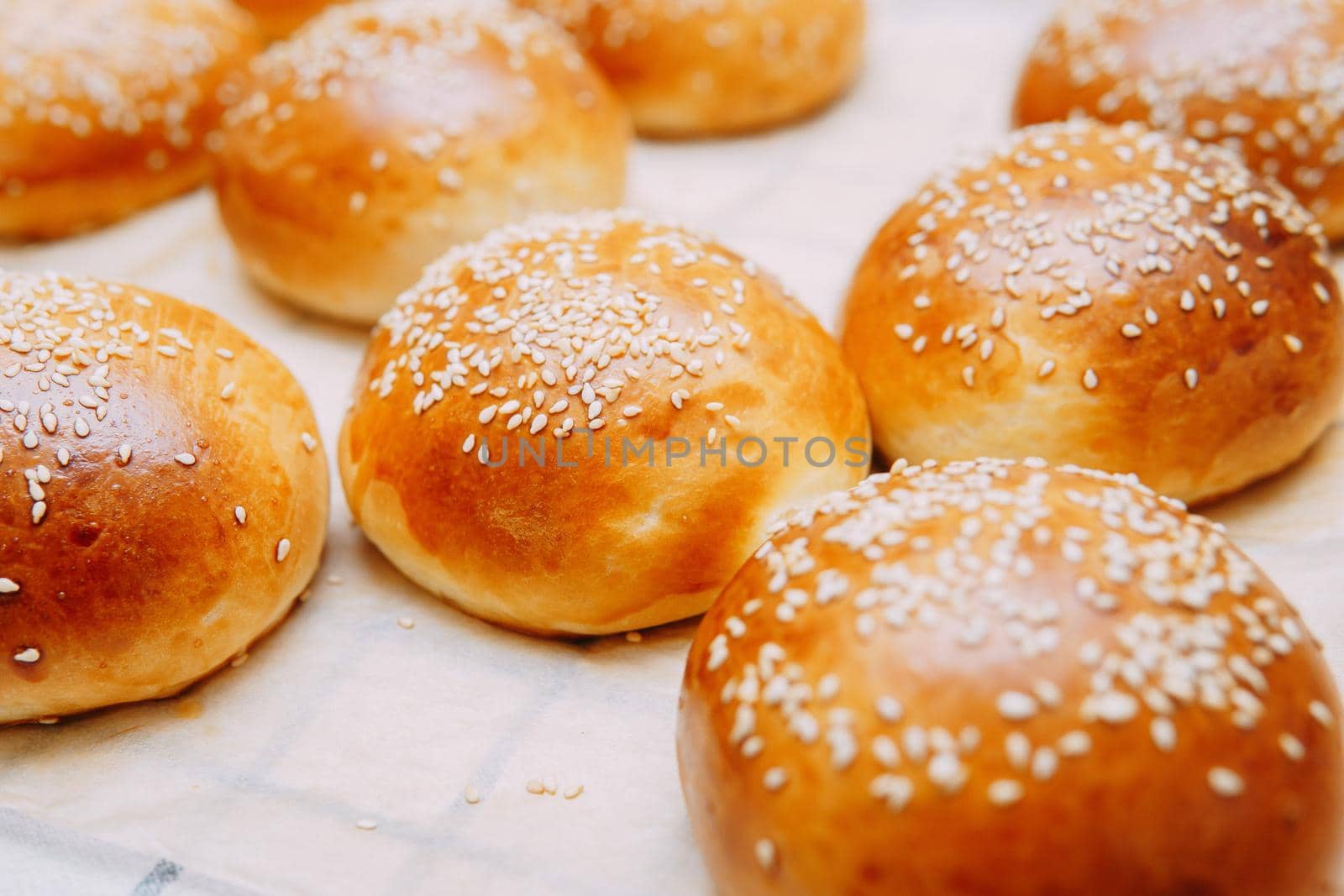 Freshly baked burger buns with sesame seeds. We cook at home.