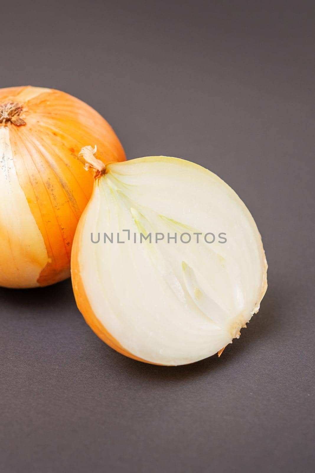 Two unpeeled whole and half raw yellow onions on black surface. Flat lay. Copy space