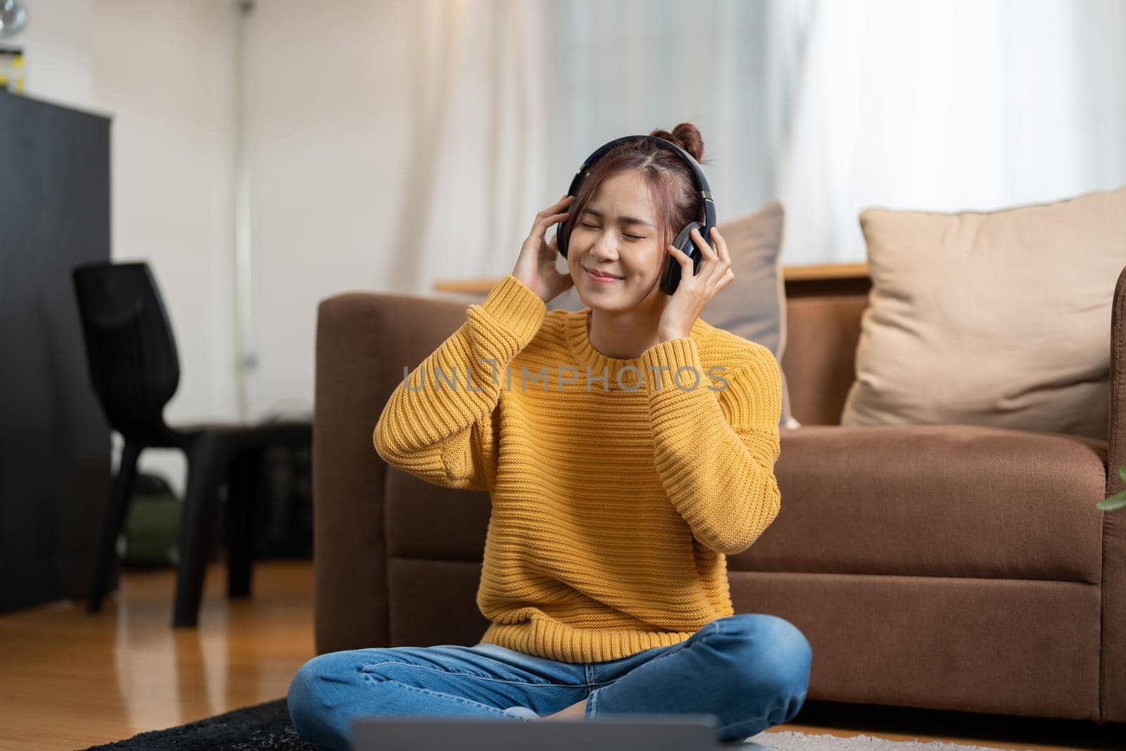 Young beautiful woman in yellow outfit enjoying the music at home by nateemee