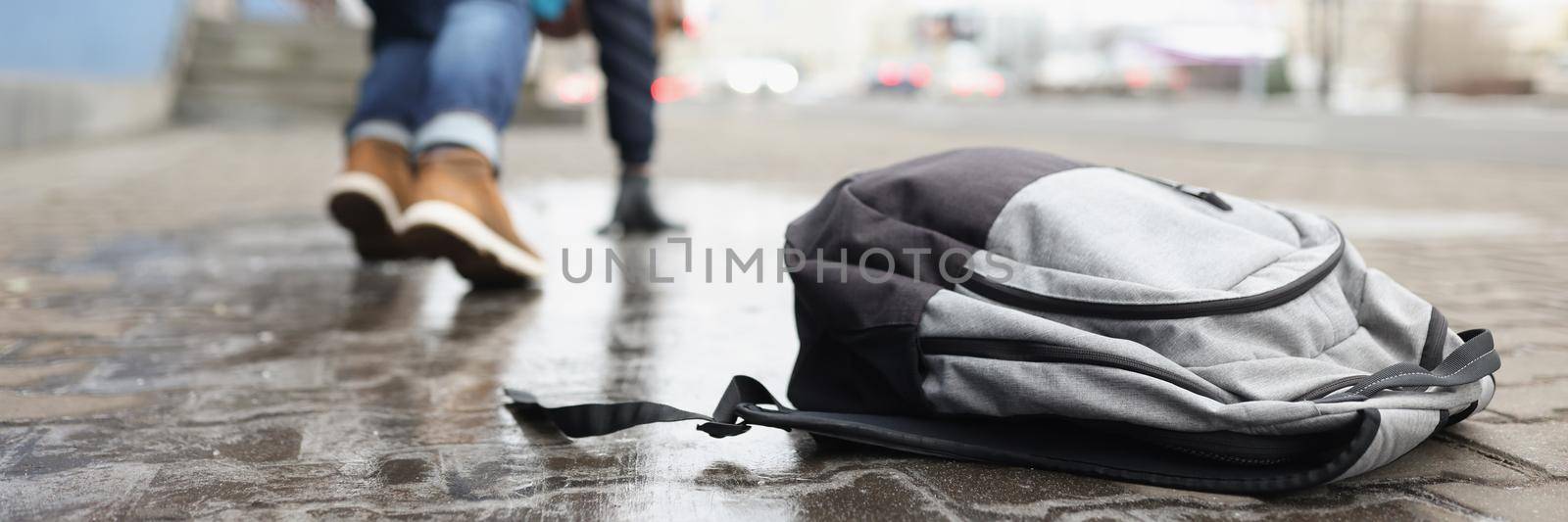 Close-up of man almost fell on ground because of slippery weather. Backpack with personal things on asphalt. Winter, weather conditions, trauma concept