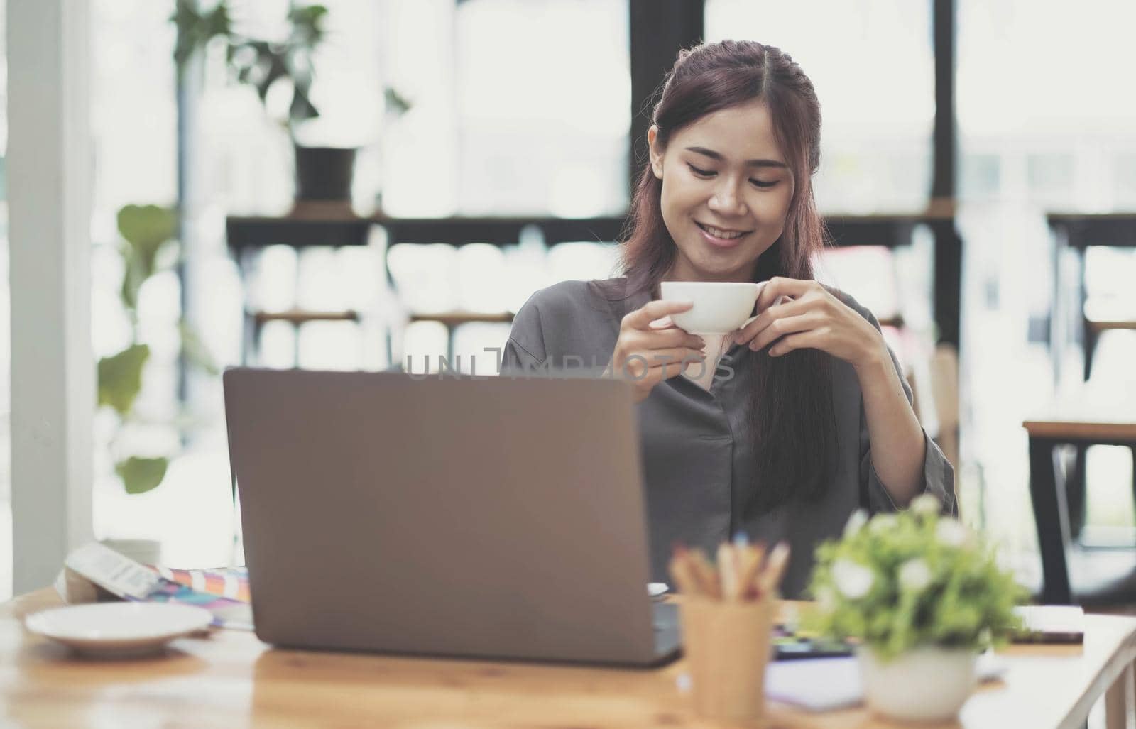 female hand working with digital tablet and holding coffee cup on dark creative workspace. by wichayada