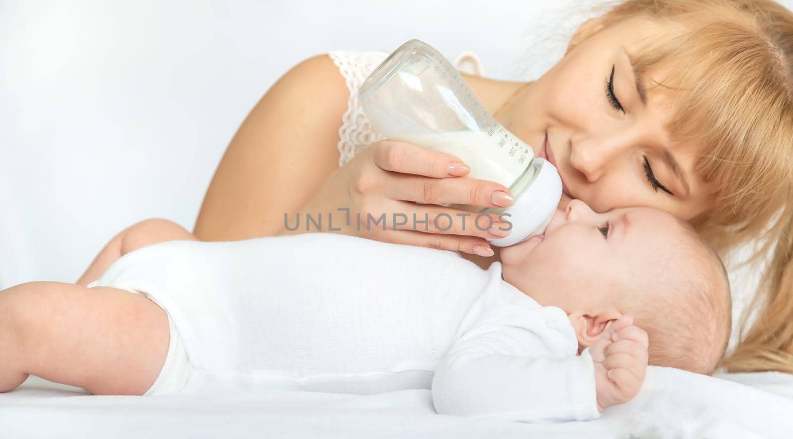 Mother feeds the baby from a bottle. Selective focus. People.