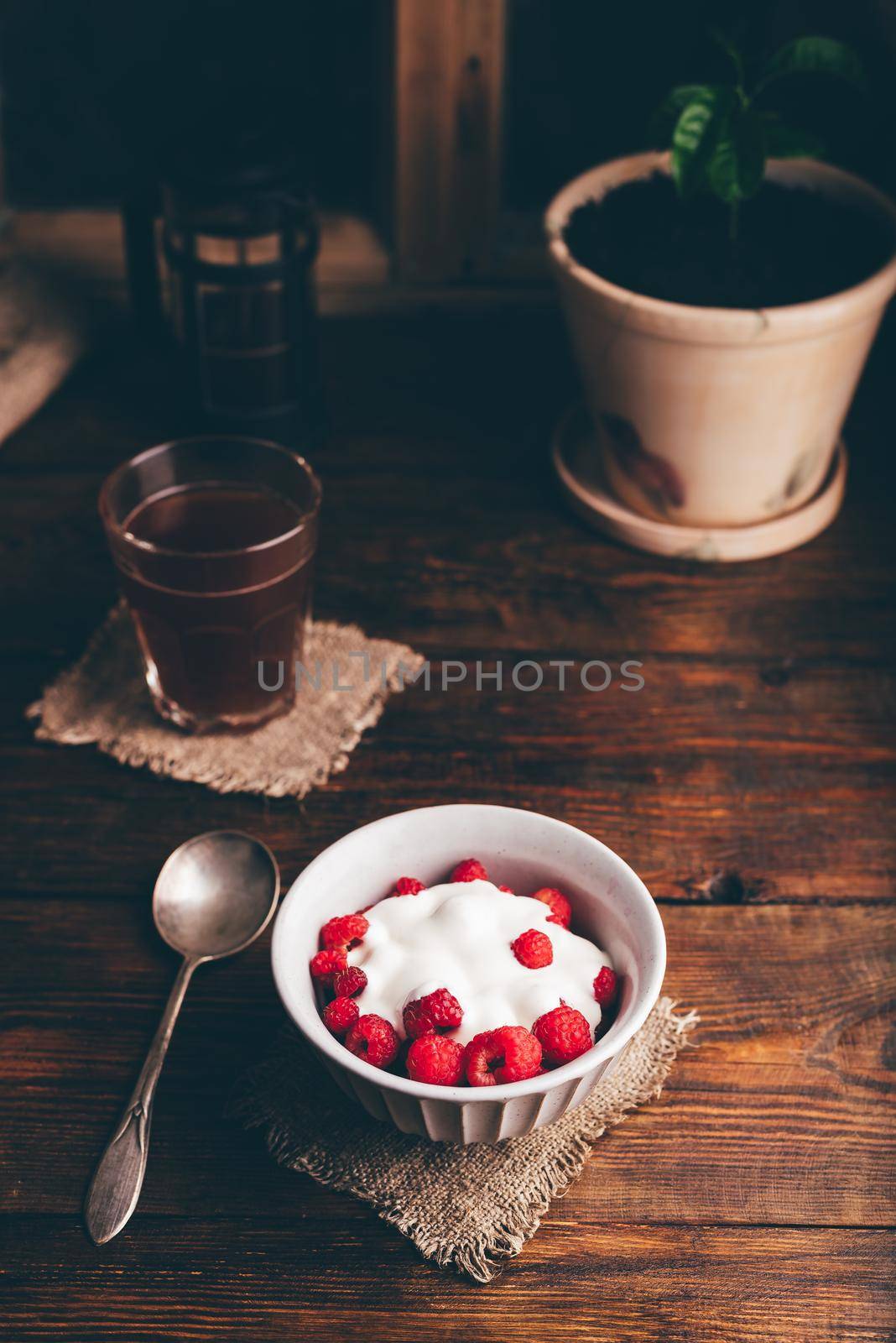 Bowl of Summer Dessert with Fresh Raspberry and Cream and Glass of Coffee on Rustic Surface