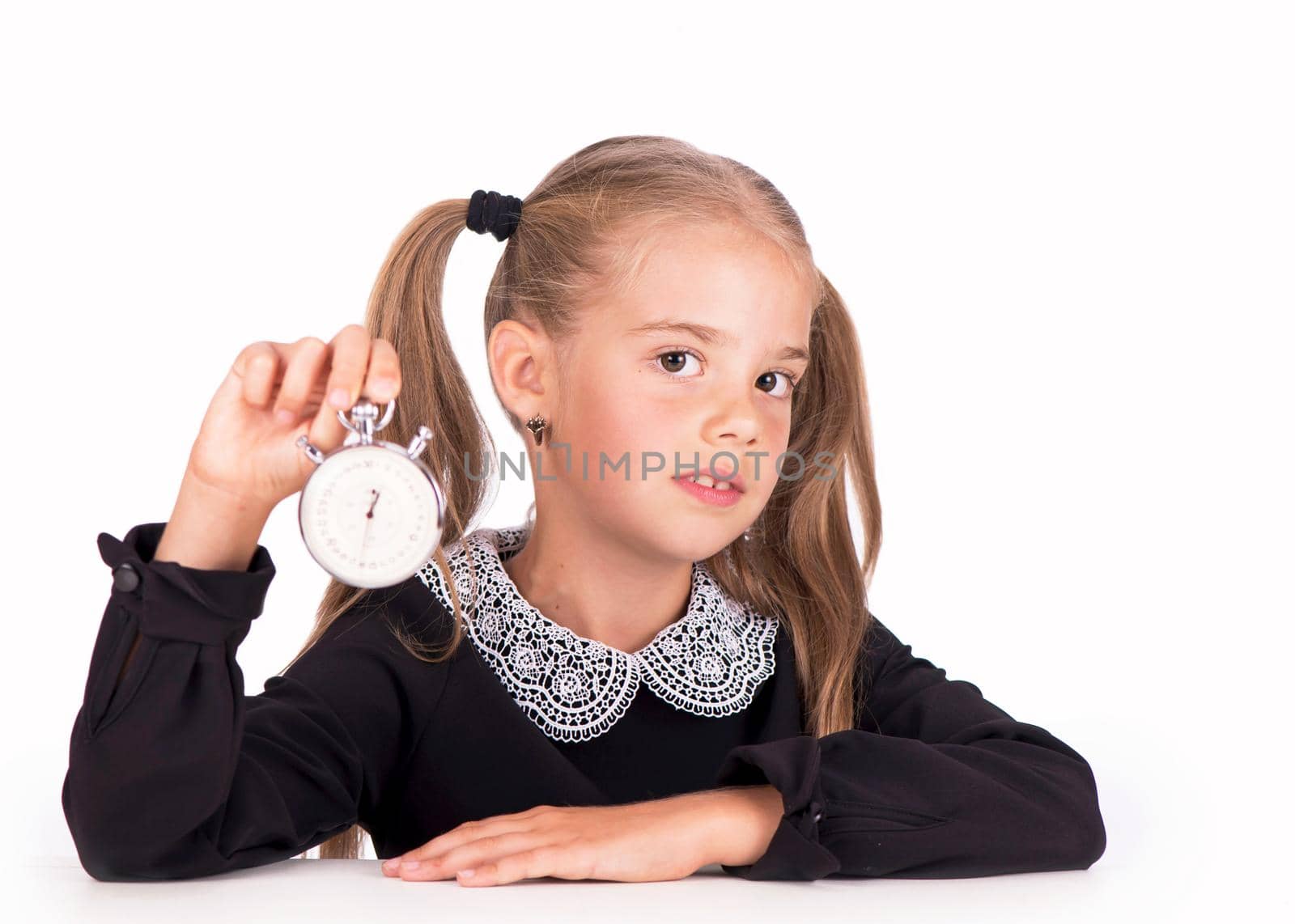 Little girl, blonde in a school dress points to a stopwatch on a white background by aprilphoto