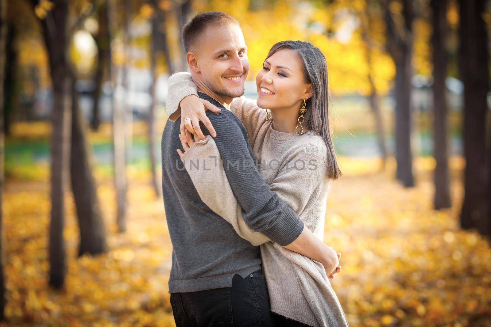 Young international couple hugging on a date in autumn city park by Rom4ek