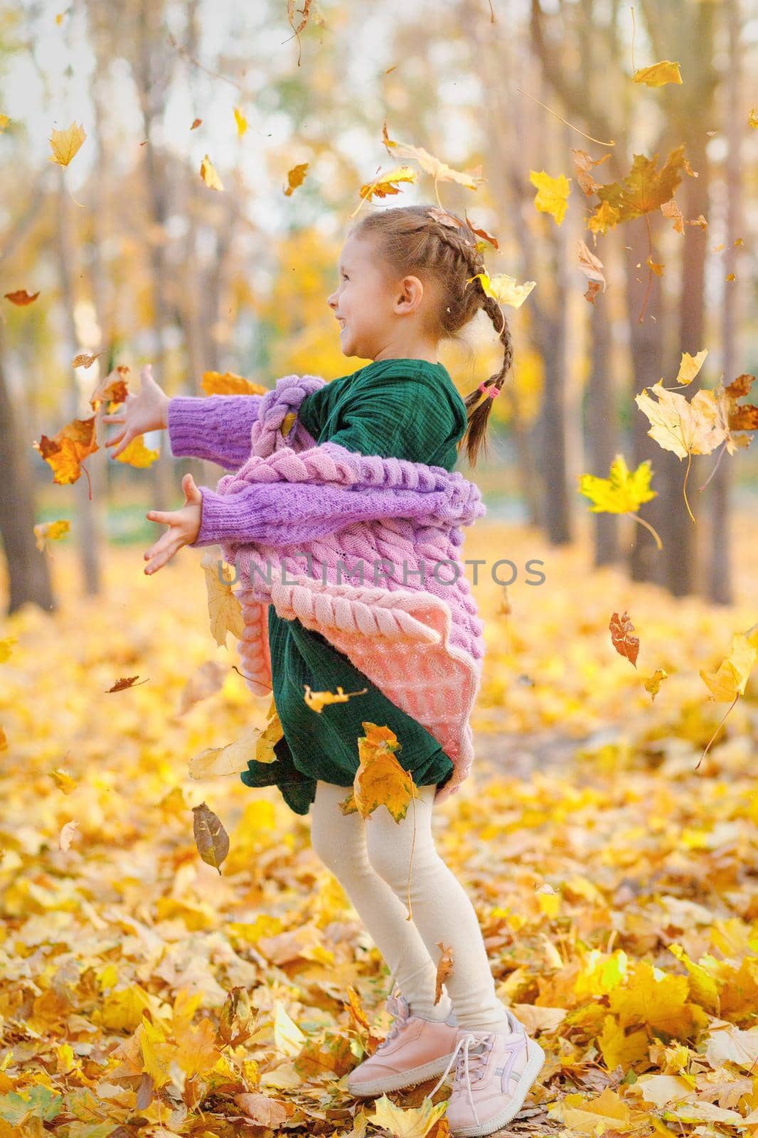 Happy cauxasian girl smiling joyful throws up autumn leaves outside in fall forest.