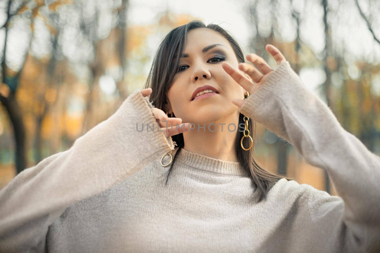 Portrait of young dancing woman in autumn gray sweater in autumn park.