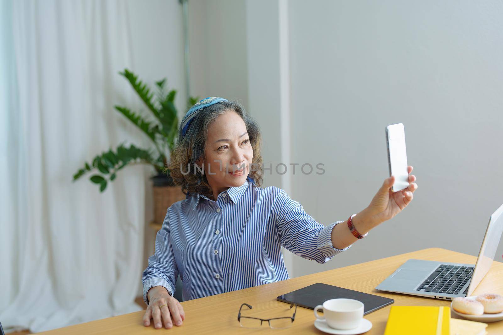 Portrait of an elderly woman talking to a friend on the phone during a coffee break.