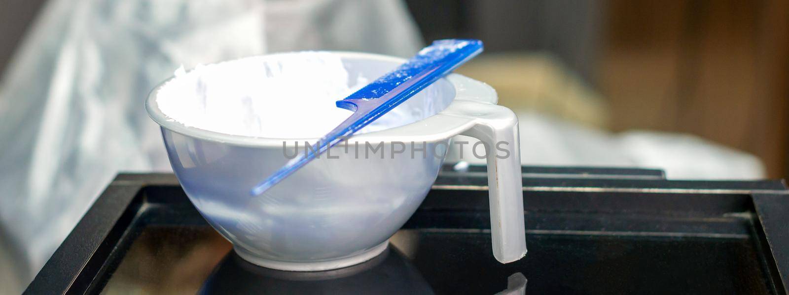 White hair dye in container on the special table in hair salon