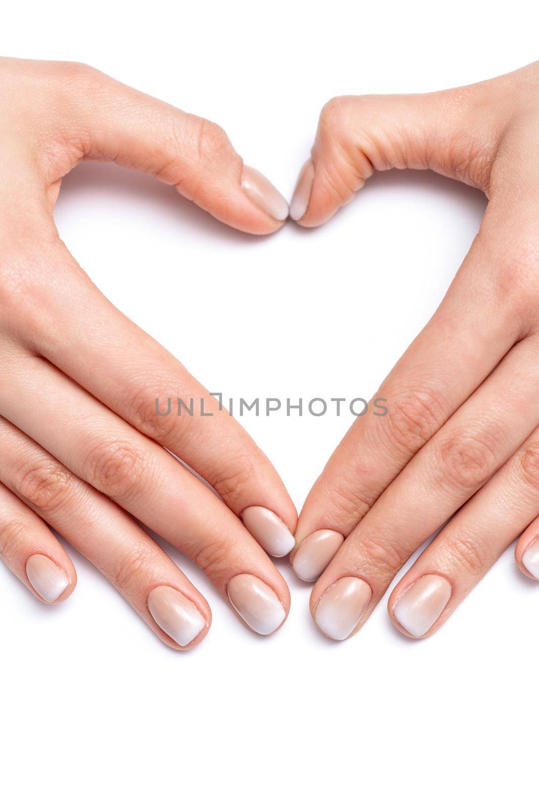 Closeup of hands of young woman forming shape of heart with her manicured fingers on white background