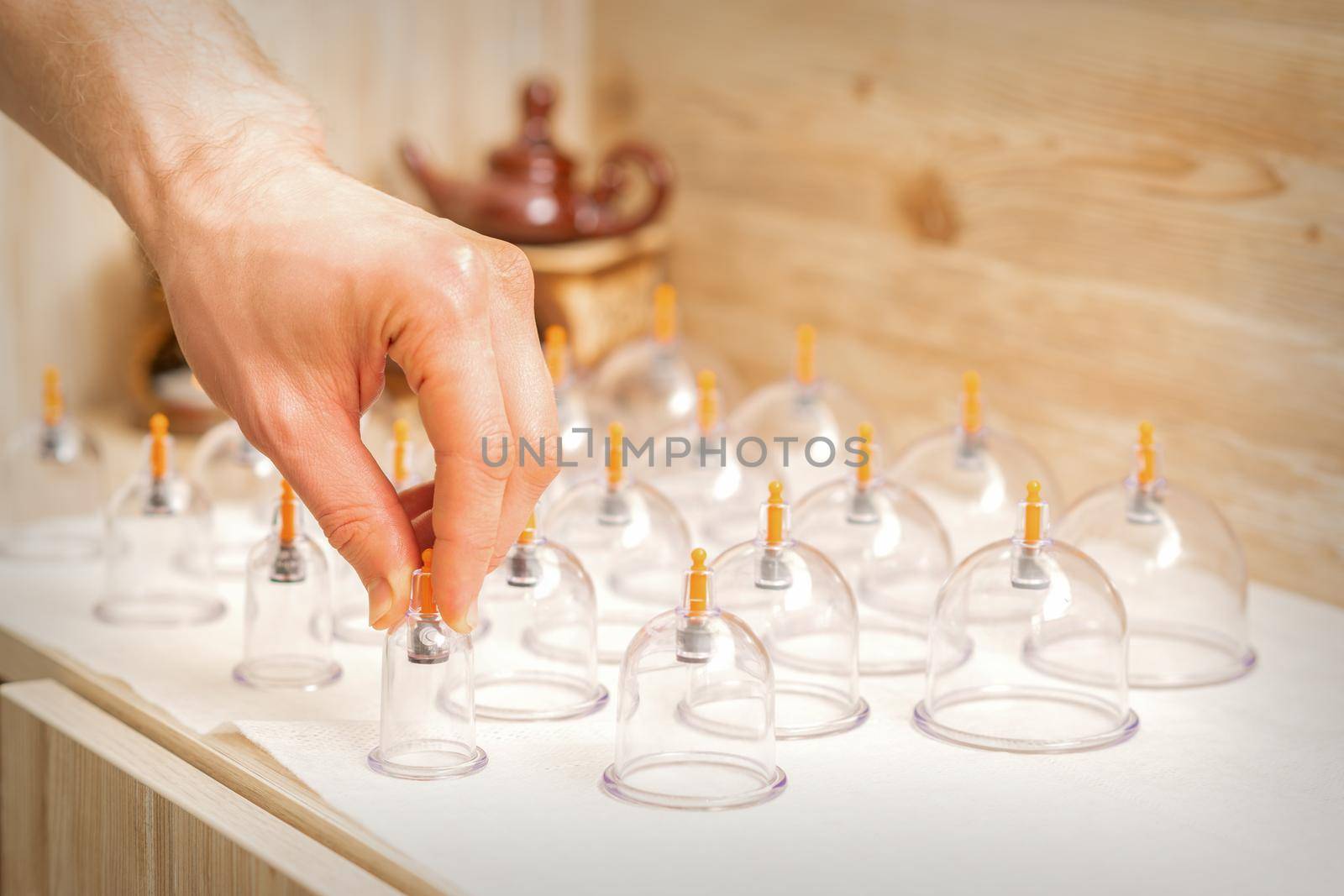Masseur takes vacuum massage glass jars of traditional Chinese cupping therapy from table in spa