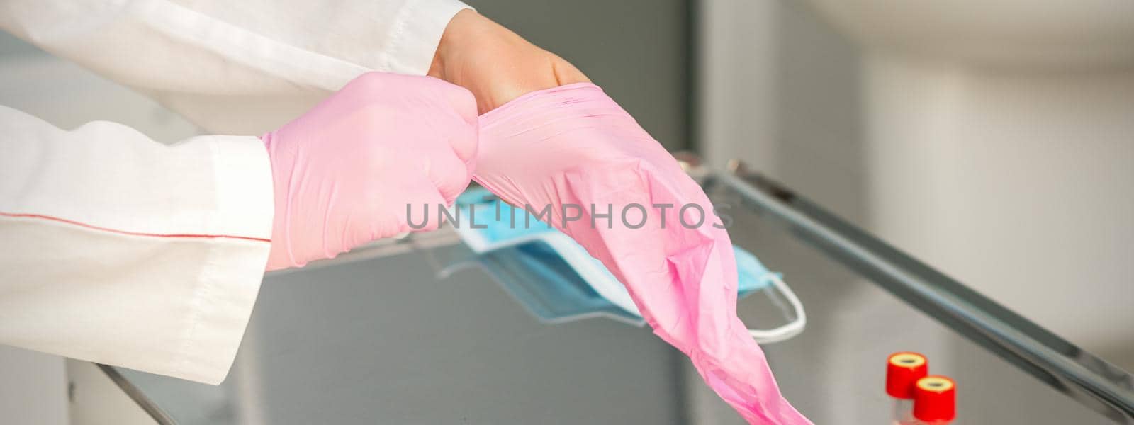 Female doctor wearing rubber protective gloves on her hands in the lab