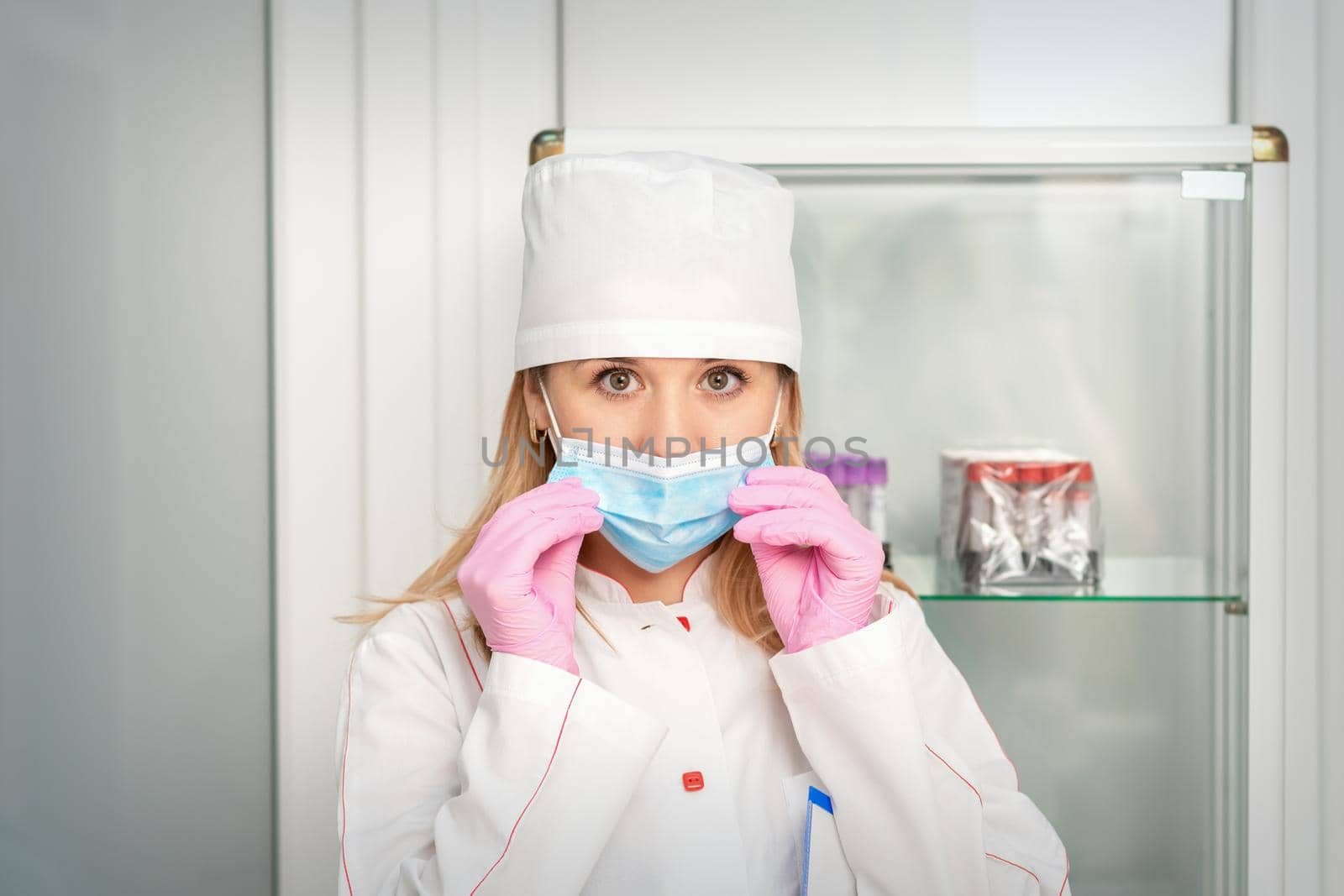 Female nurse or doctor wears protective gloves putting on medical face mask in the lab