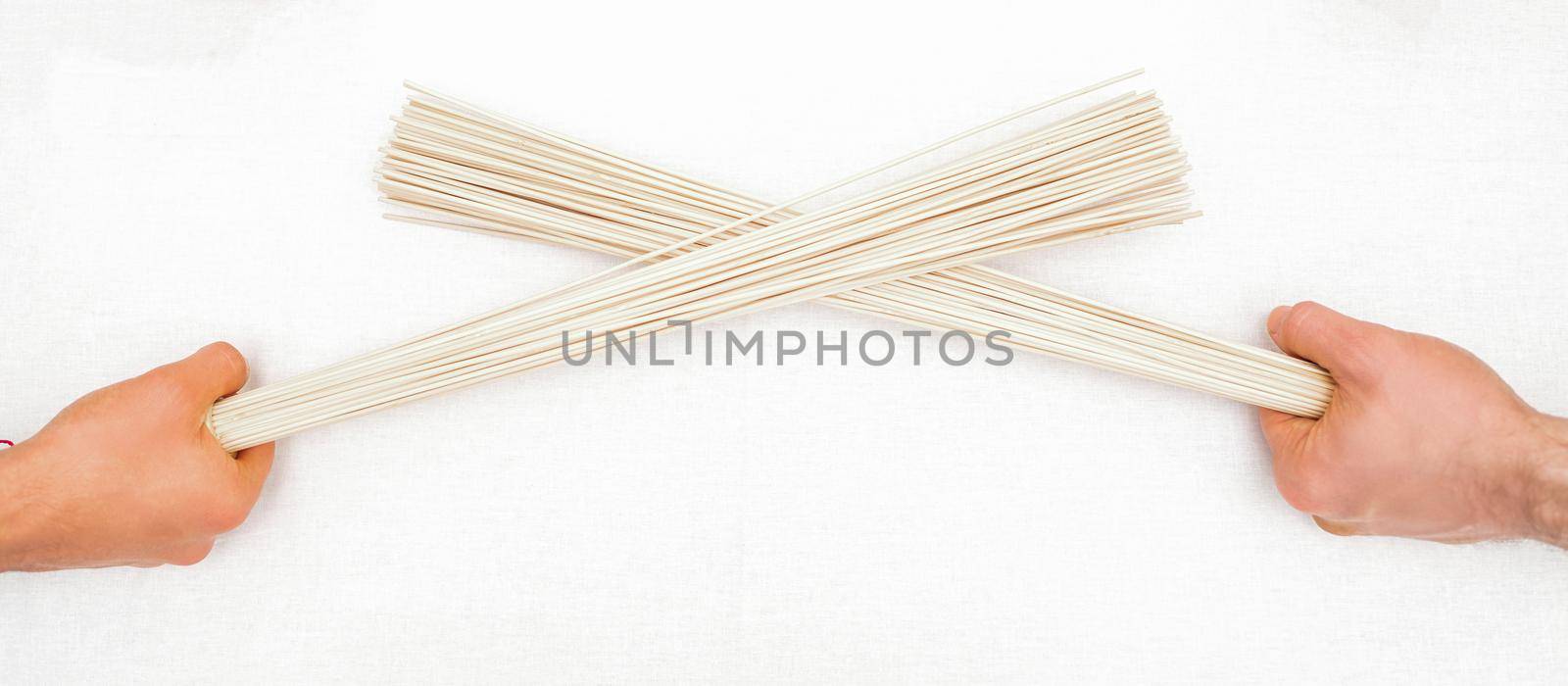Bamboo massage brooms in hands of two masseurs isolated on white background