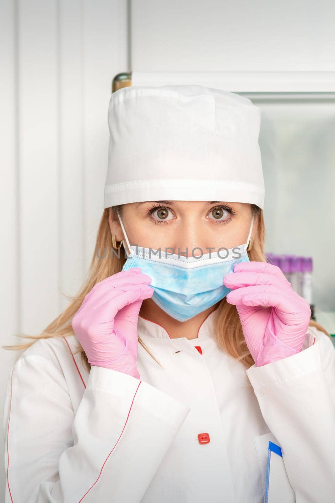 Female nurse or doctor wears protective gloves putting on medical face mask in the lab