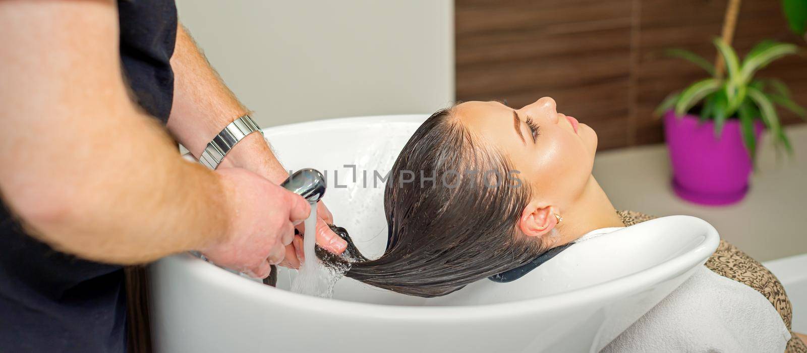 Hairdresser rinses hair of woman by okskukuruza
