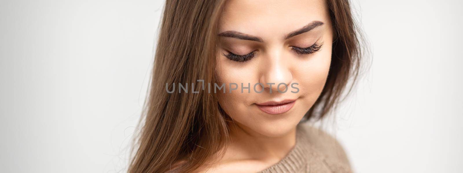 Portrait of beautiful young caucasian woman with closed eyes after eyelash extension procedure and permanent makeup