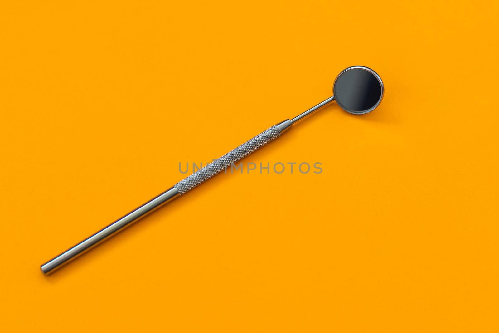 Dental mirror on an orange background. Medical tool by Andelov13