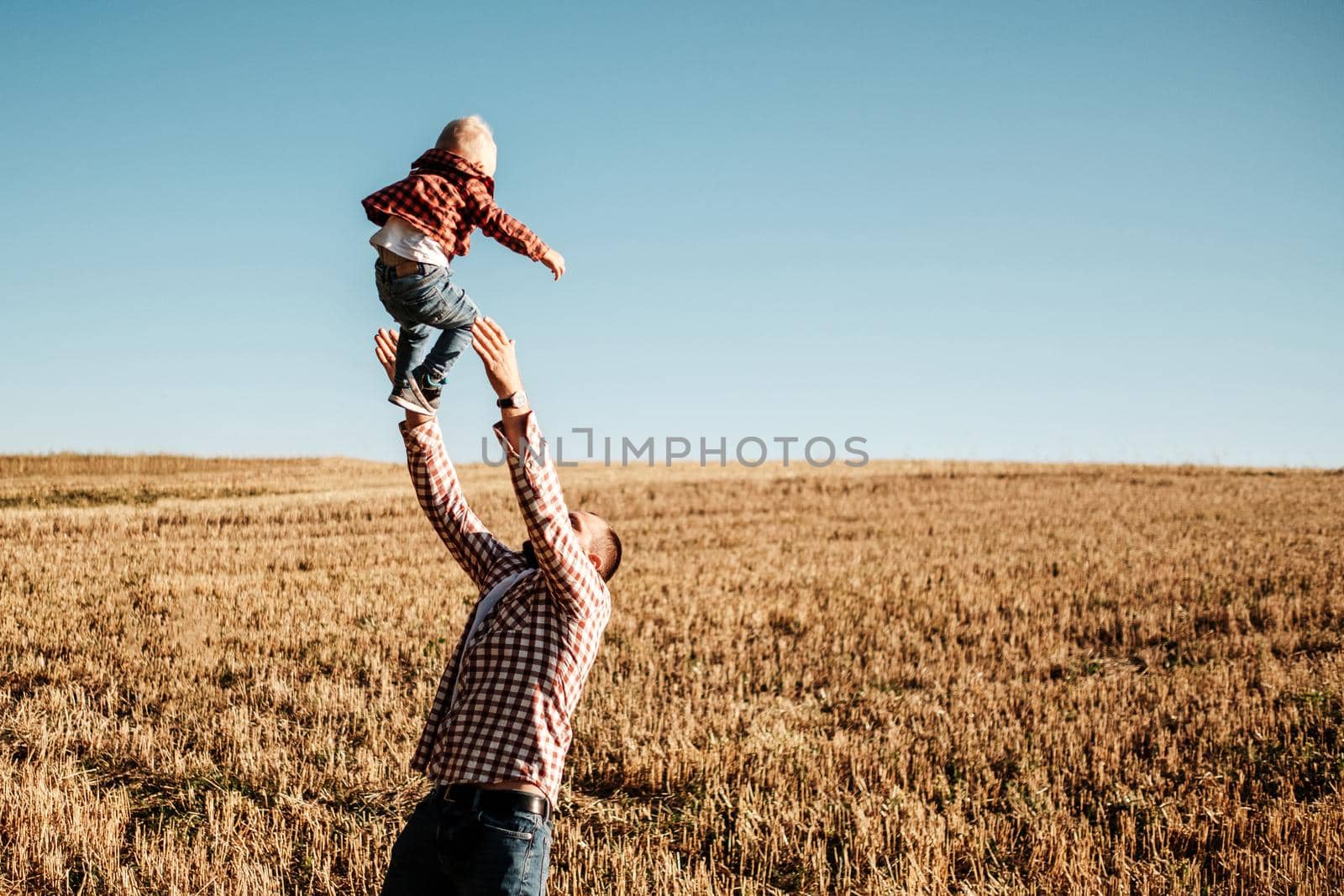 Happy Dad with His Little Son Enjoying Summer Weekend Outside City in the Field at Sunny Day Sunset