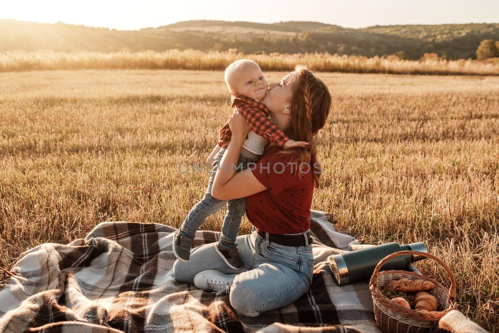 Happy Mom with Her Little Son Enjoying Summer Weekend Outside City in the Field at Sunny Day Sunset