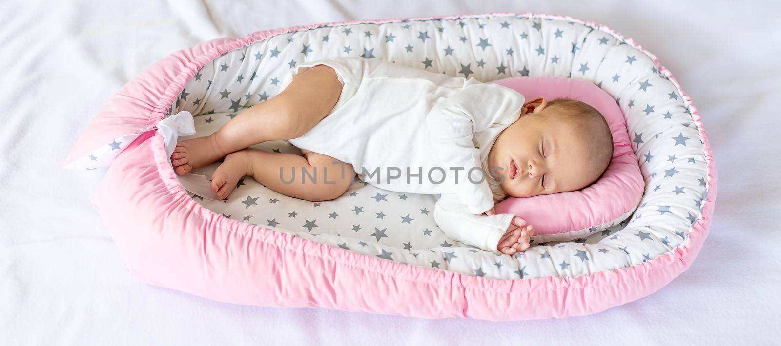 A newborn baby sleeps in a cocoon. Selective focus. People.