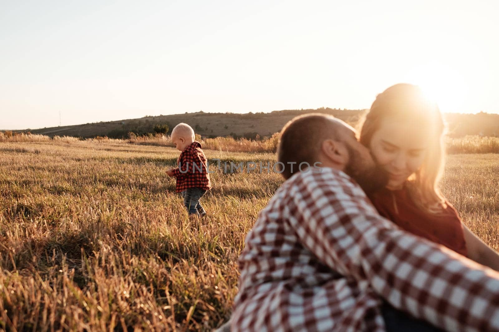 Happy Young Family Mom and Dad with Their Little Son Enjoying Summer Weekend Picnic Outside the City in Field at Sunny Day Sunset, Vacation Time Concept