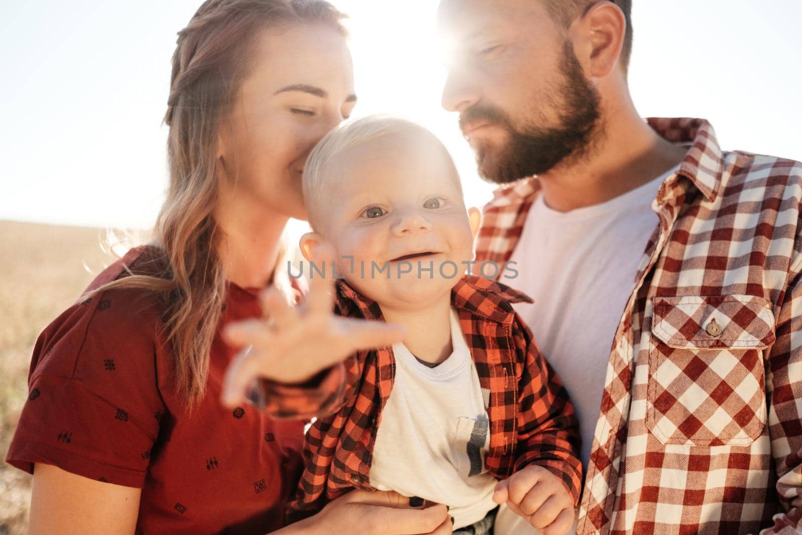 Happy Young Family Mom and Dad with Their Little Son Enjoying Summer Weekend Picnic Outside the City in Field at Sunny Day Sunset, Vacation Time Concept