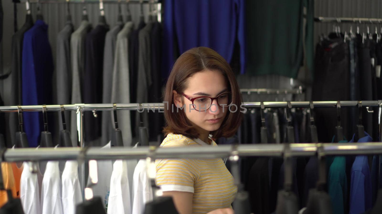 Young woman chooses clothes in the store. Clothing store. 4k