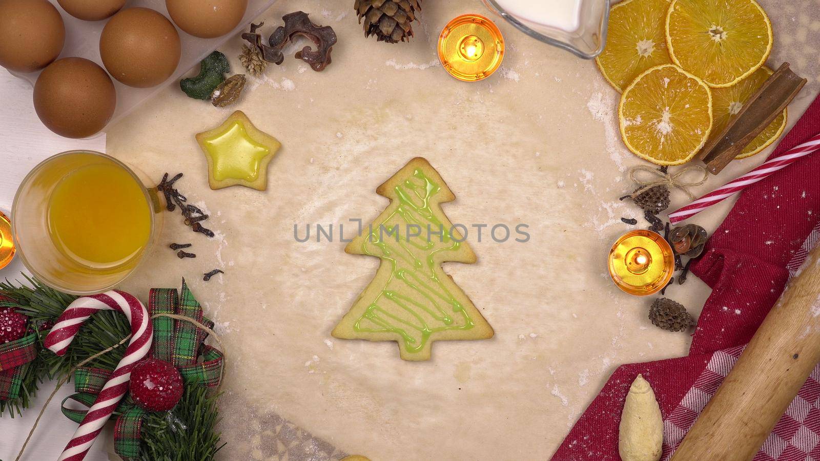 A young woman decorates a festive Christmas cookie in the form of a Christmas tree with colored icing. View from above. 4k