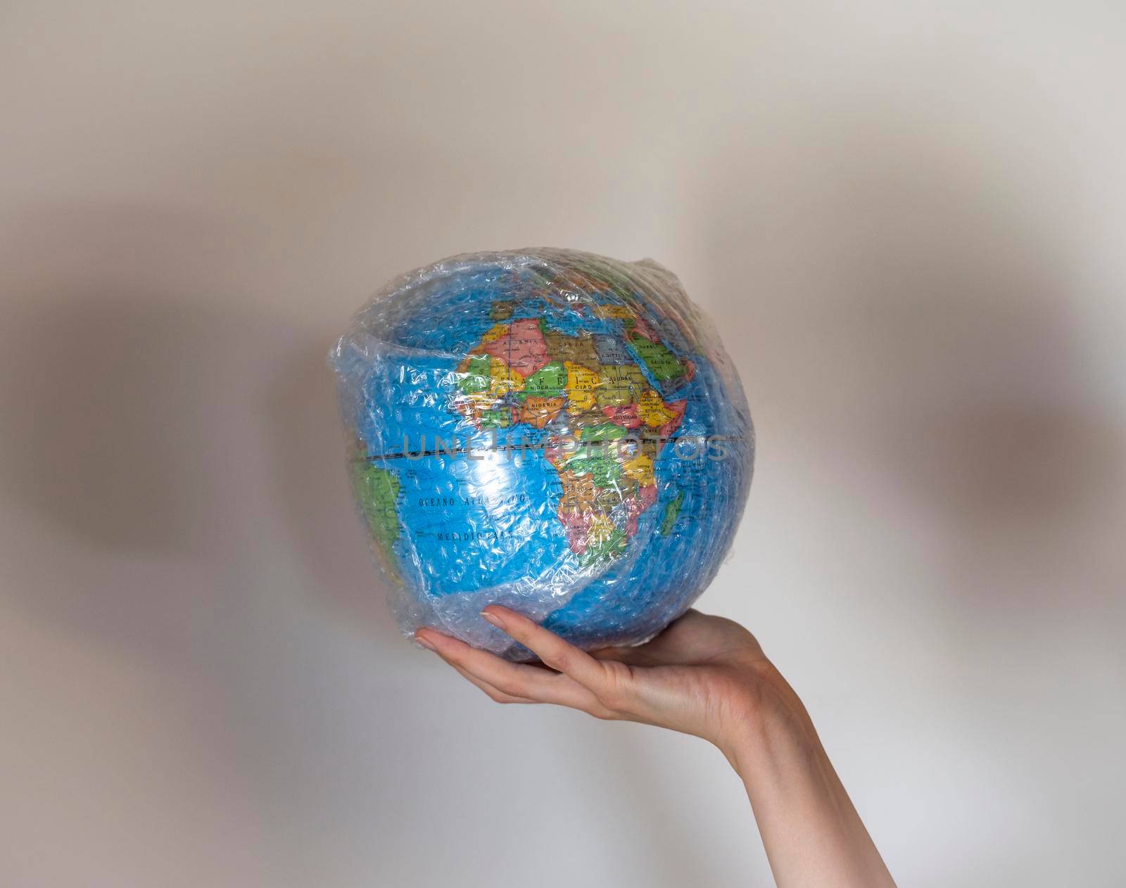 Hand holds a globe wrapped in plastic bubble wrap.