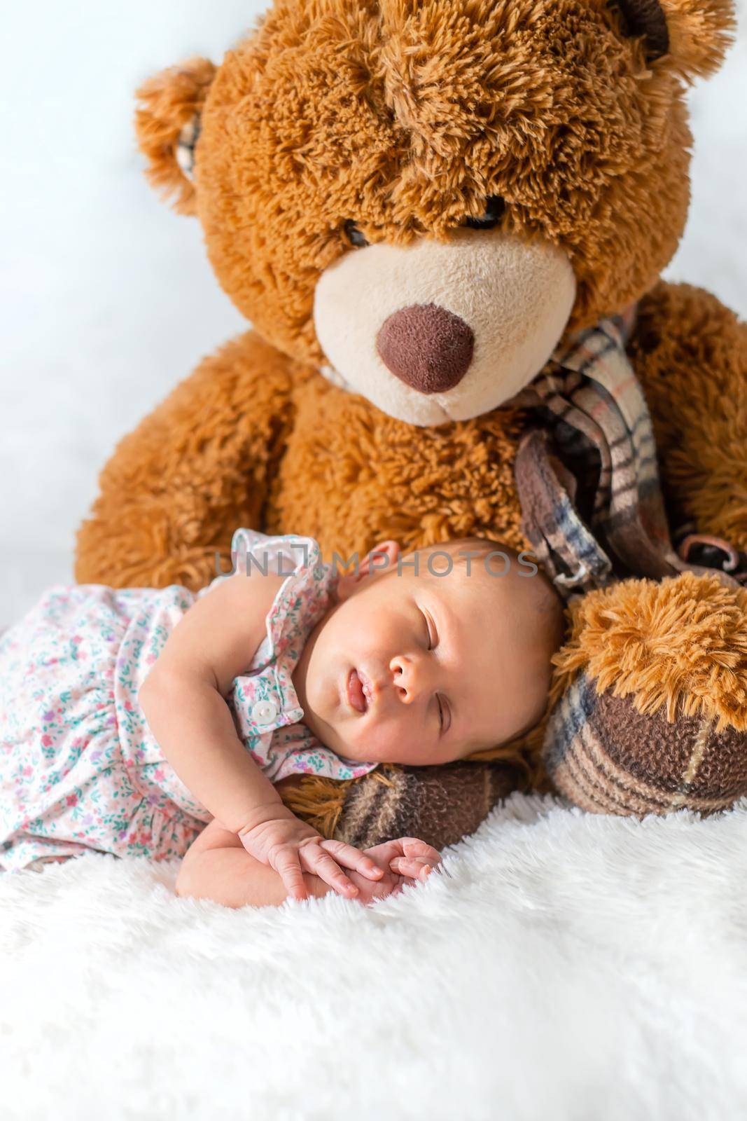 A newborn baby sleeps with a teddy bear. Selective focus.