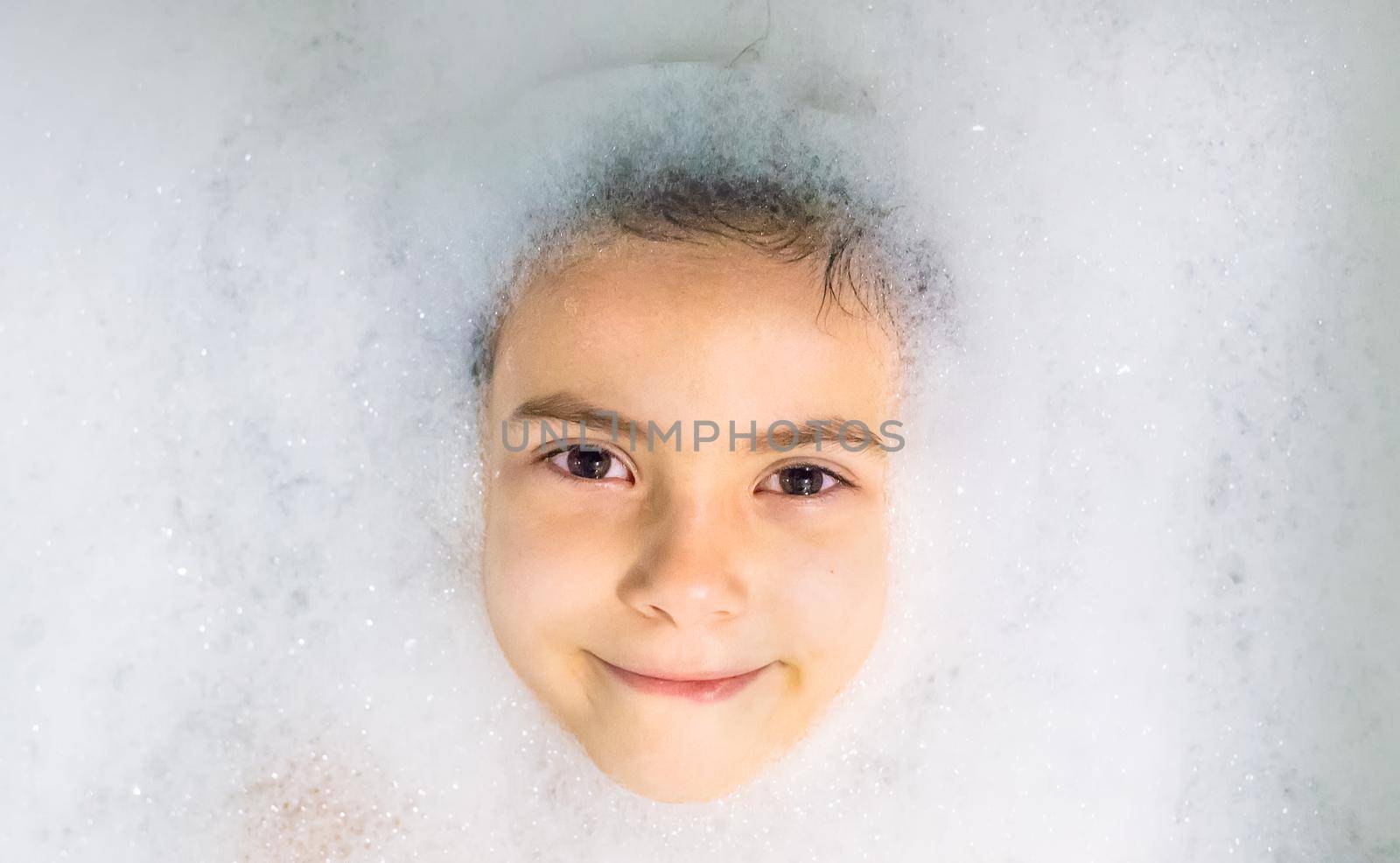 The child bathes in a bathtub soapy water. Selective focus.