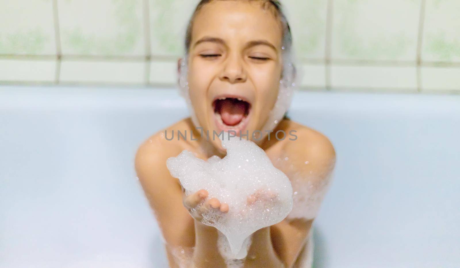 The child bathes in a bathtub soapy water. Selective focus.