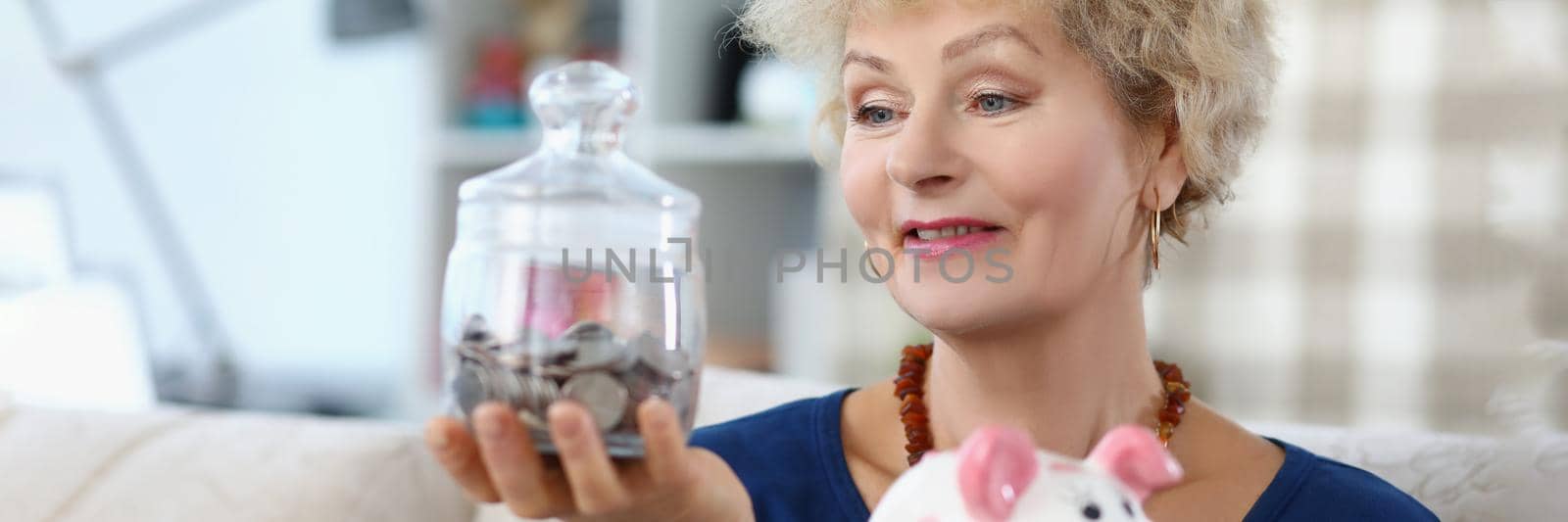 Senior woman hold glass container with saved money for retirement by kuprevich