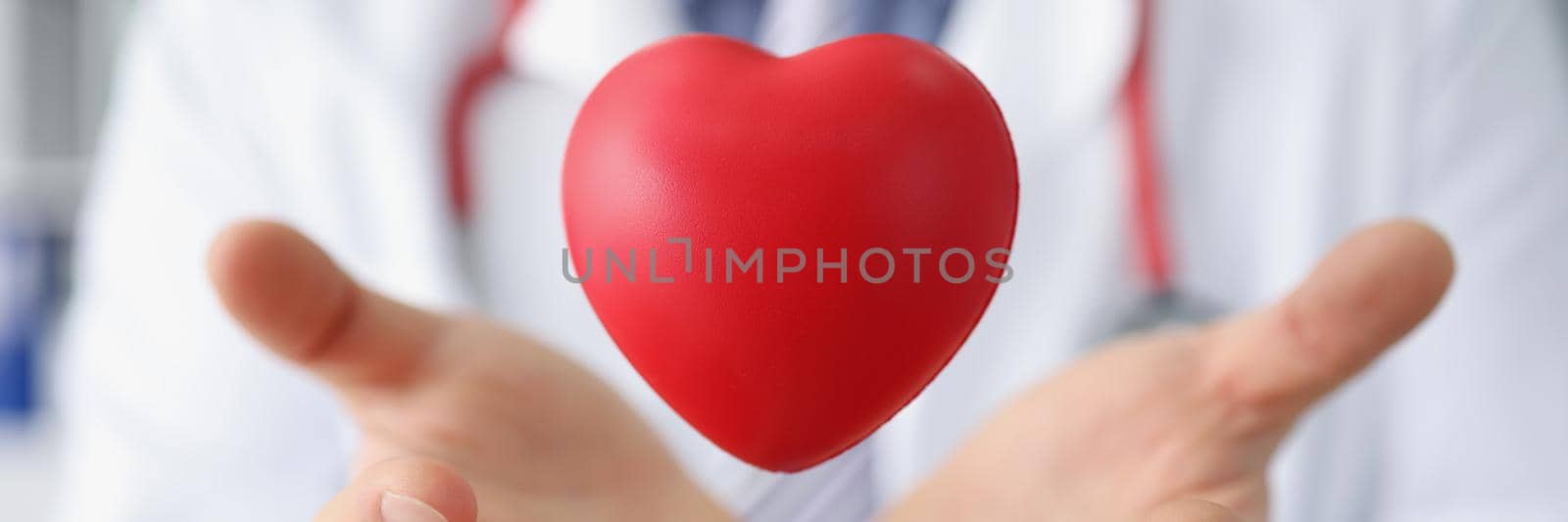 Medical worker throw red plastic heart and catch it in palms by kuprevich