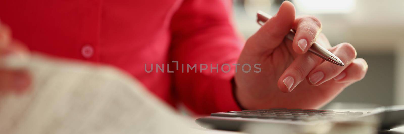 Close-up of woman calculating total amount of expense at end of month. Woman use calculator, checks and pen for notes. Bill, finance, family budget concept