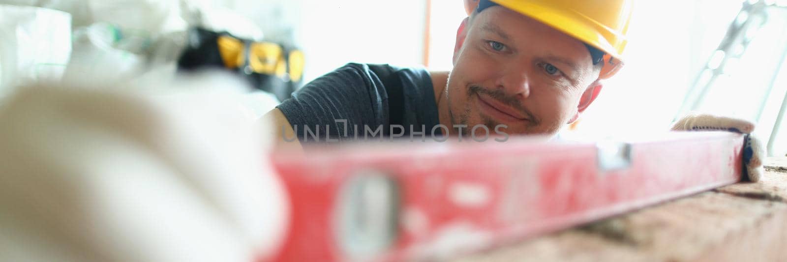 Close-up of pedantic man using level tool to measure height of brick wall. Skilled professional bricklayer work on project. Construction site, plan concept