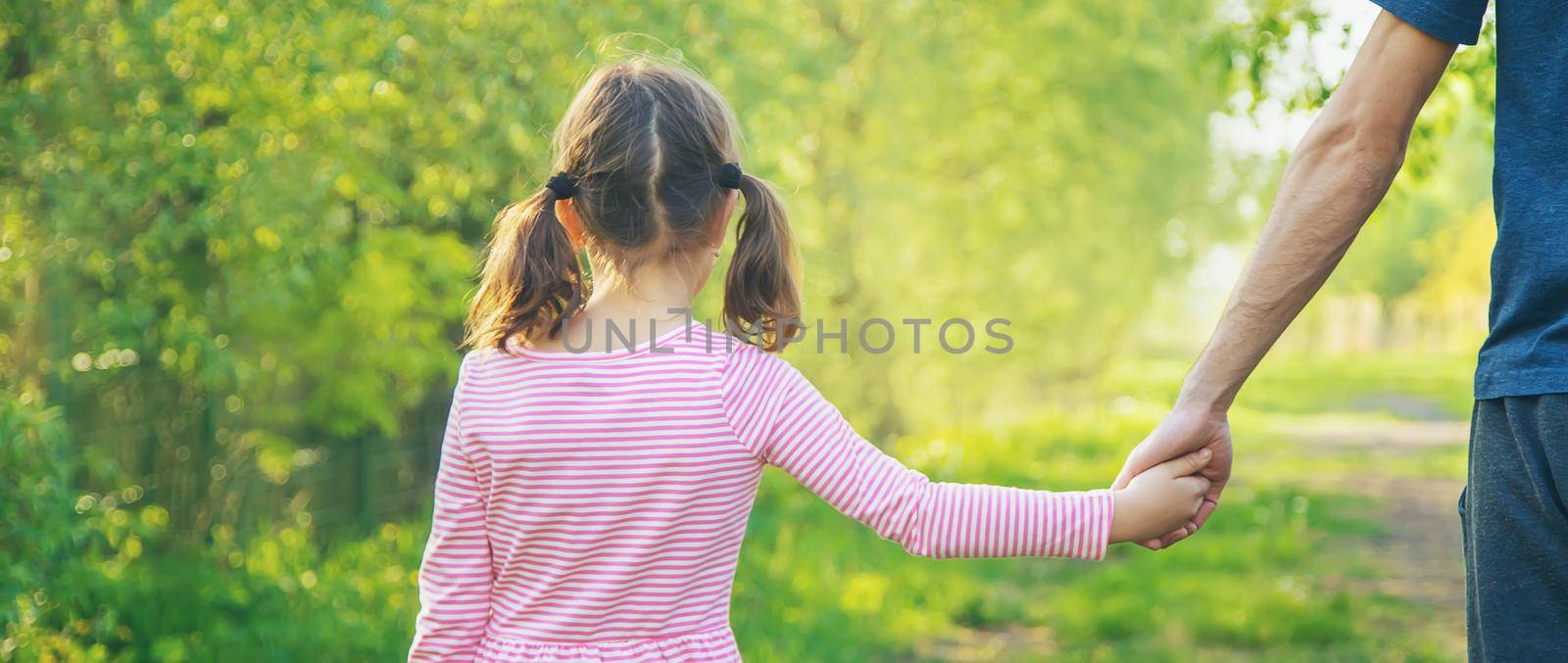 A child with his father goes by the hand. Selective focus by yanadjana