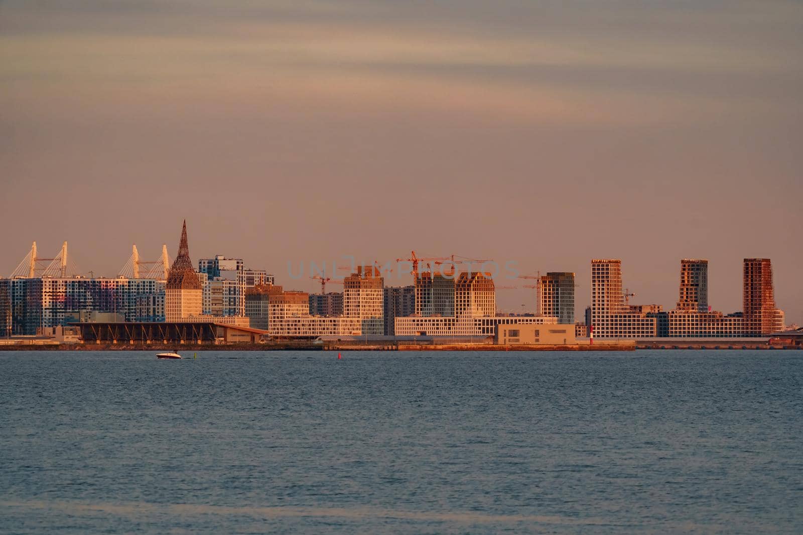 The residential complex under construction on the embankment of the Neva River on Vasilievsky island in sunset, bulk island, construction cranes. High quality photo