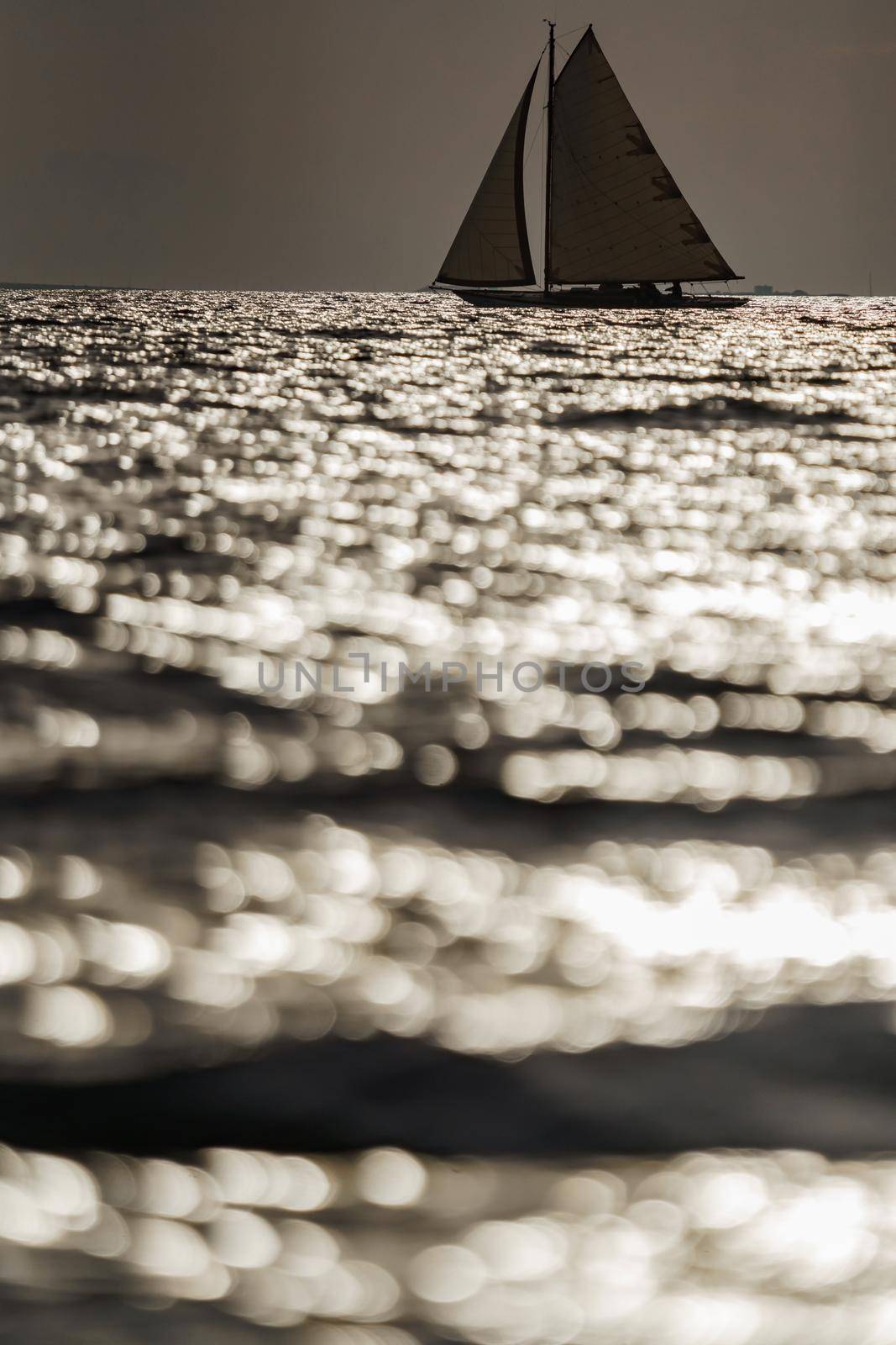 Classic sailing yacht in sea at sunset, the clear sky, sun reflection on water. High quality photo