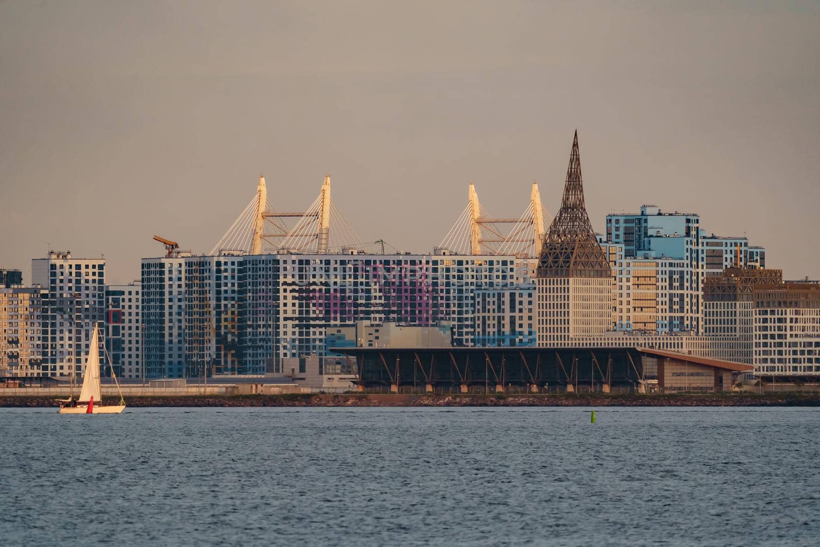 The residential complex under construction on the embankment of the Neva River on Vasilievsky island in sunset, bulk island, construction cranes. High quality photo