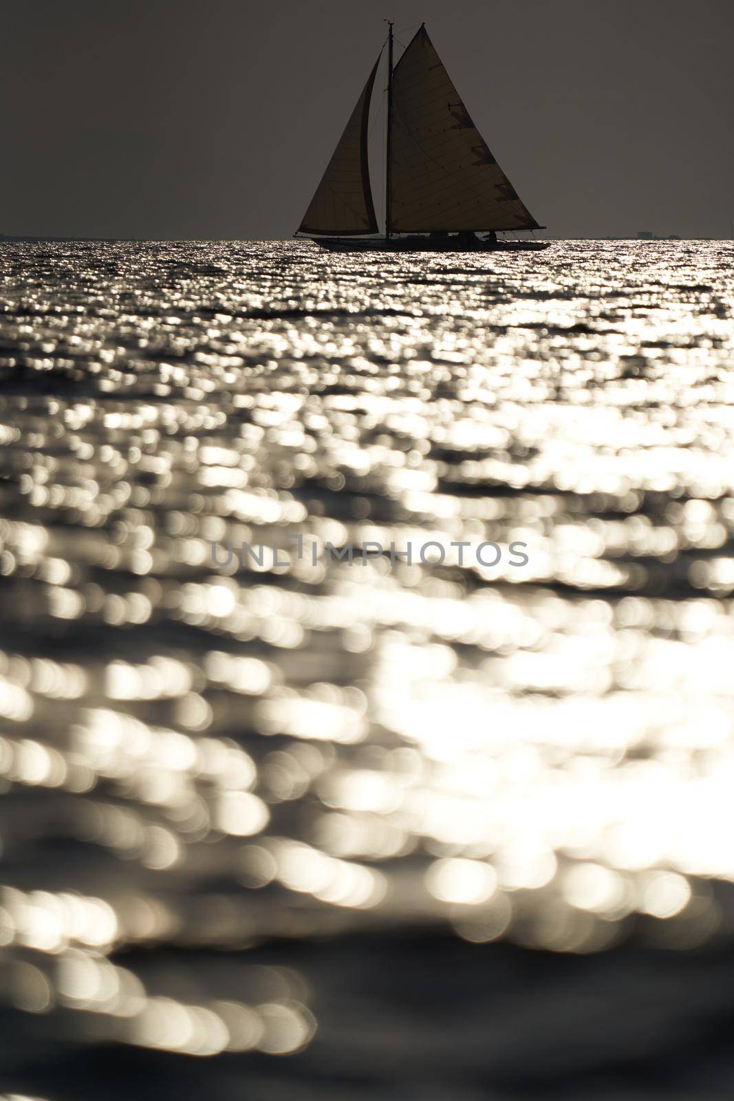 Classic sailing yacht in sea at sunset, the clear sky, sun reflection on water. High quality photo