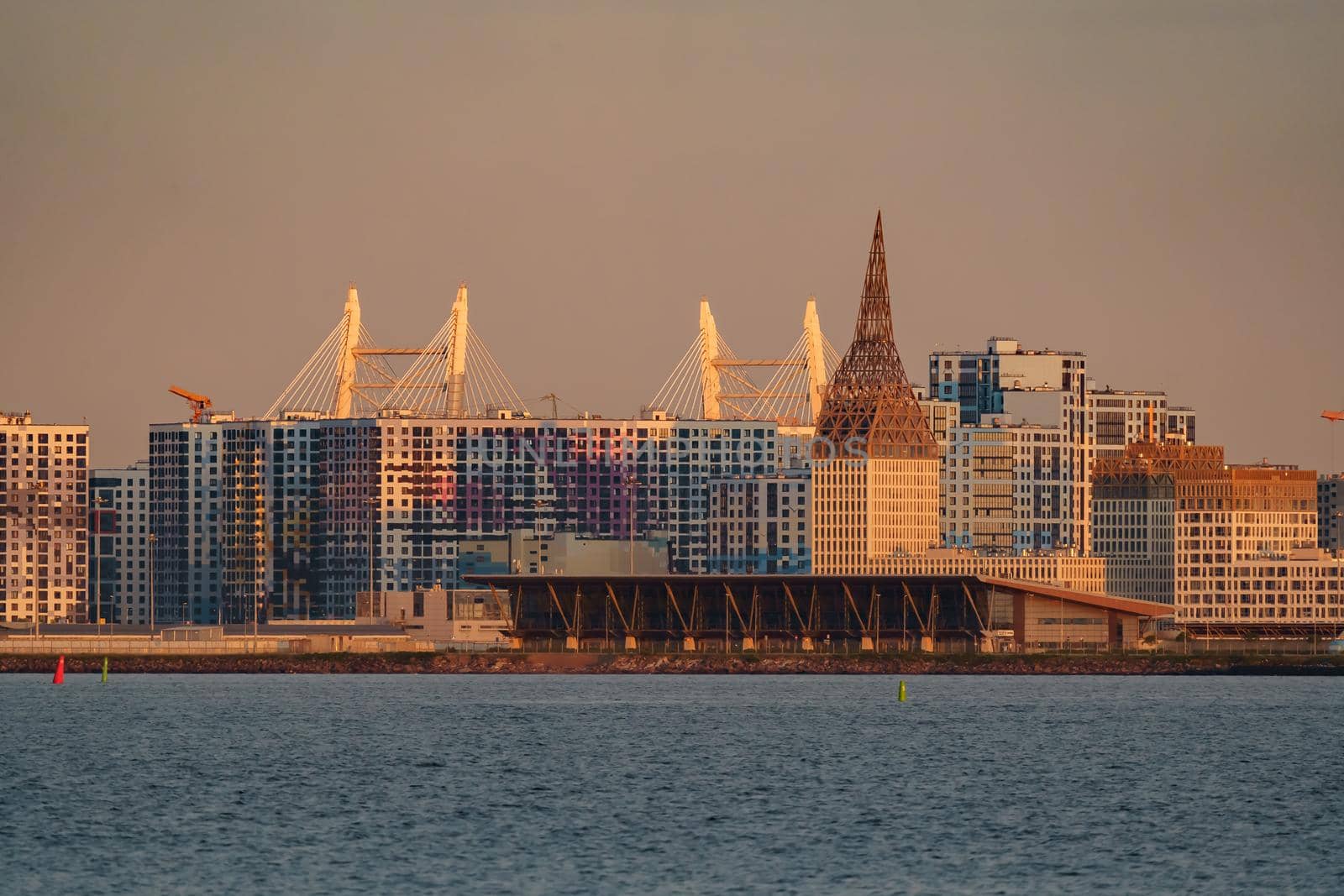 The residential complex under construction on the embankment of the Neva River on Vasilievsky island in sunset, bulk island, construction cranes. High quality photo